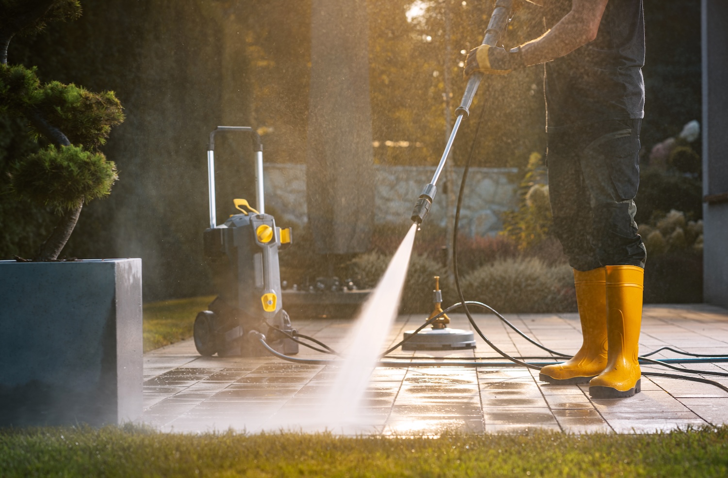 professional Power Washing a Patio With a Pressure Washer in a Sunny Outdoor Setting